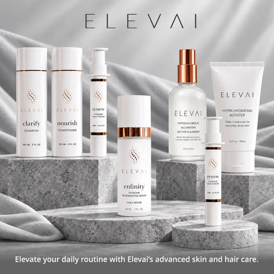 A lineup of seven white and clear skincare products from Elevai with rose gold accents, arranged on gray stone steps against a draped gray fabric background. The products include shampoo, conditioner, treatment cream, cleanser, hydrating serum, and a hydrating booster.