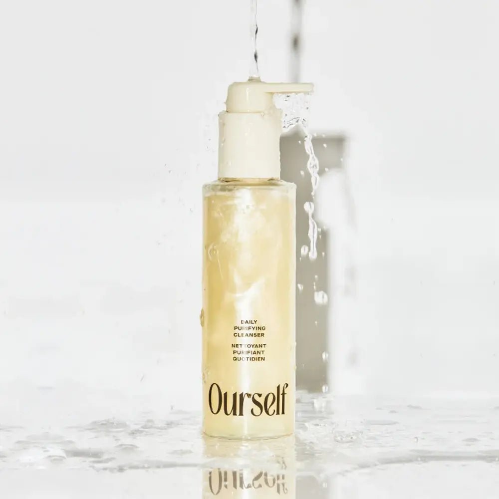Skincare bottle labeled 'Ourself' with water flowing over it on a light background