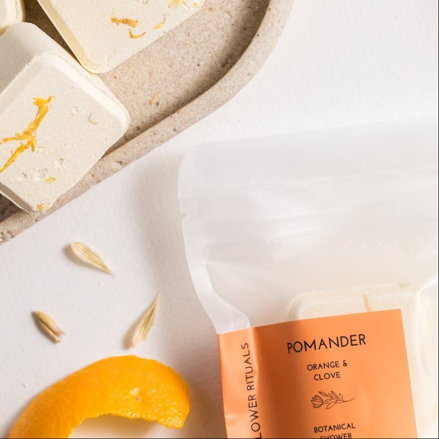 Pomander botanicals with orange rind on a textured plate with a white background.