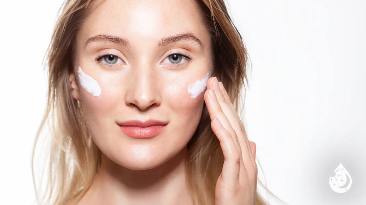Woman with cream on her cheeks applying moisturizer after a microneedling treatment