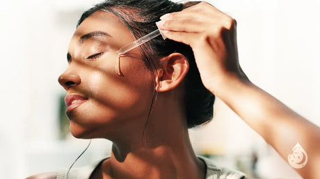 Woman applying serum on her face with shadows and sun rays on her face