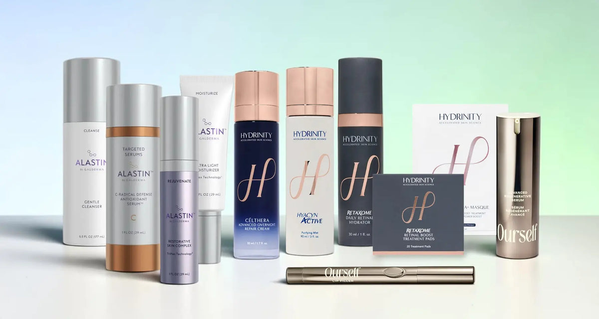 A collection of Hydrinity skincare products arranged on a white surface against a soft green-to-blue gradient background. The products include various bottles, tubes, and boxes in white, silver, blue, and rose gold tones, with a slim metallic tube placed in front.