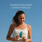 A smiling woman in a white tank top holds a small teal travel-sized supplement pouch against a clear blue sky. White text at the top reads, 'Supplements made to travel with you.