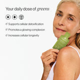 Woman holding a green supplement package with text about its benefits on a white background