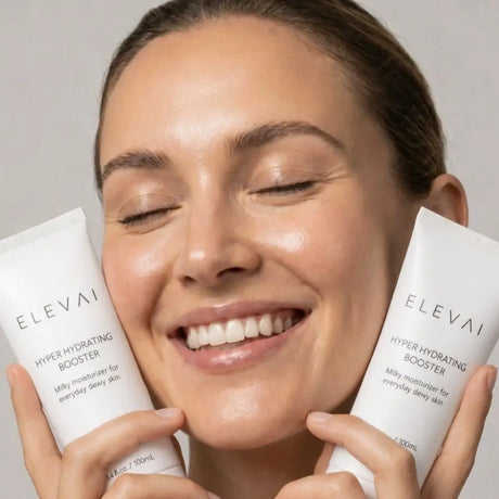 Smiling woman with dewy, hydrated skin holding two tubes of Elevai Hyper Hydrating Booster