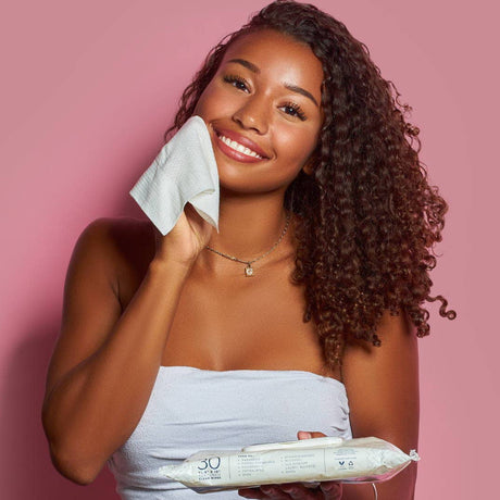 Woman holding a package of wipes with a pink background