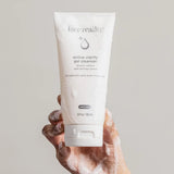 Hand with rich foam holding a tube of Face Reality Active Clarity Gel Cleanser