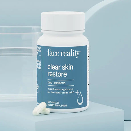 Supplement bottle labeled 'face reality clear skin restore' on a light blue background
