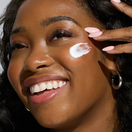 Woman applying Face Reality SPF 30 Plus  to her face with a close-up focus on her skin texture.