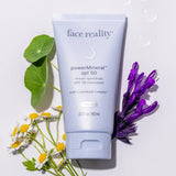 Tube of 'face reality' powerMineral SPF 50 sunscreen with flowers on a light background
