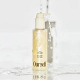Skincare bottle labeled 'Ourself' with water flowing over it on a light background