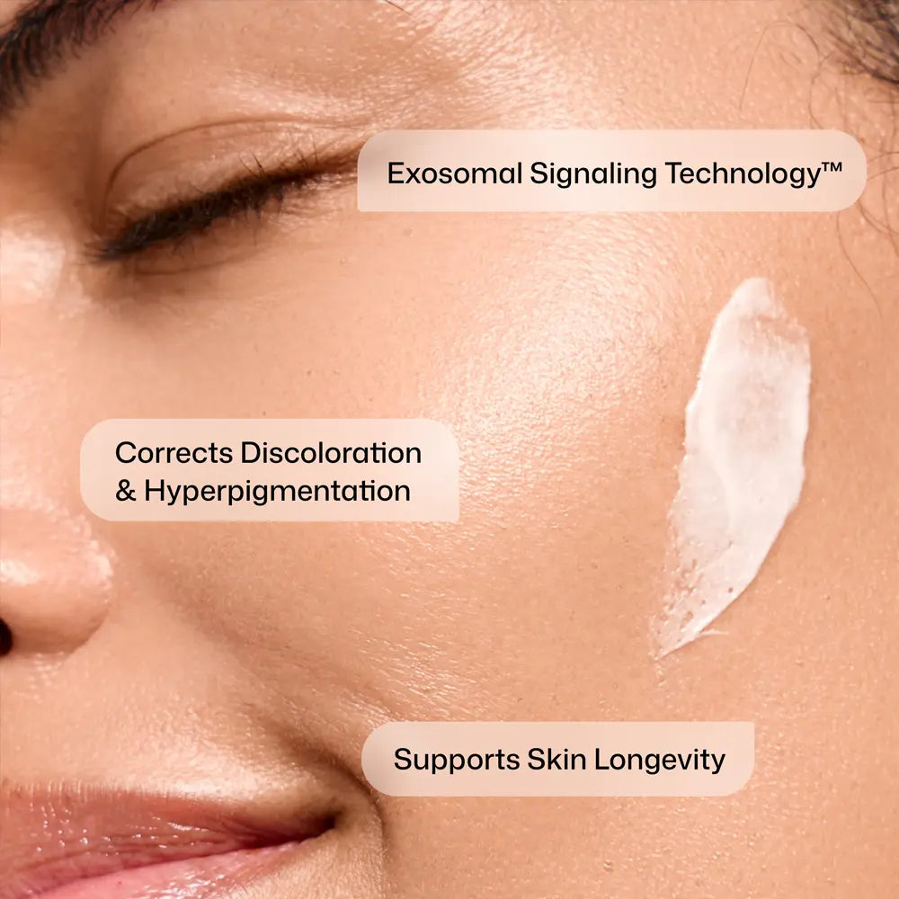Close-up of a person's face with Revision Skincare Advanced Pigment Corrector+ serum applied to the cheek and three text callouts reading 'Exosomal Signaling Technology™', 'Corrects Discoloration & Hyperpigmentation', and 'Supports Skin Longevity'.