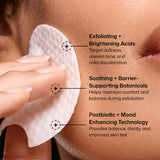 Close-up of a hand holding a Revision Skincare Tone+ Correcting Pad against a person's cheek, with three callout text panels describing skincare benefits: exfoliating and brightening acids, soothing botanicals, and postbiotic mood enhancing technology.