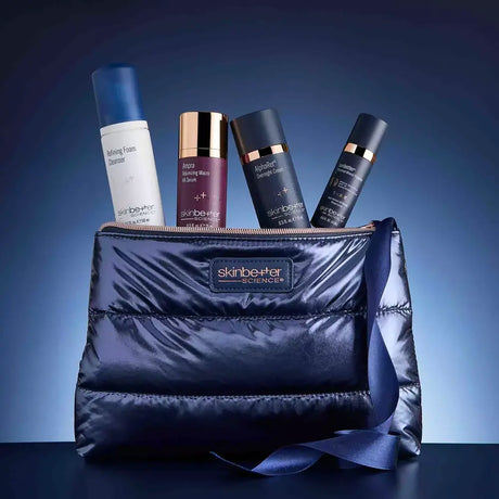 A Skinbetter Science Plump and Protect Daily Edit Set blue puffer-style cosmetic bag with a zipper and ribbon, shown with four skincare bottles and tubes protruding from the top. The bag has a visible Skinbetter logo patch.