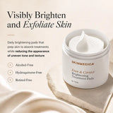 A white cosmetic jar of SkinMedica Even & Correct Brightening Treatment Pads sits on a beige stone slab with draped fabric. Text on the left reads 'Visibly Brighten and Exfoliate Skin' with product benefits listed below.