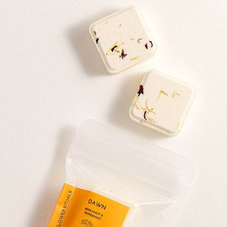 Two Dawn Shower Steamers with packaging on a light background