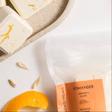 Pomander botanicals with orange rind on a textured plate with a white background.