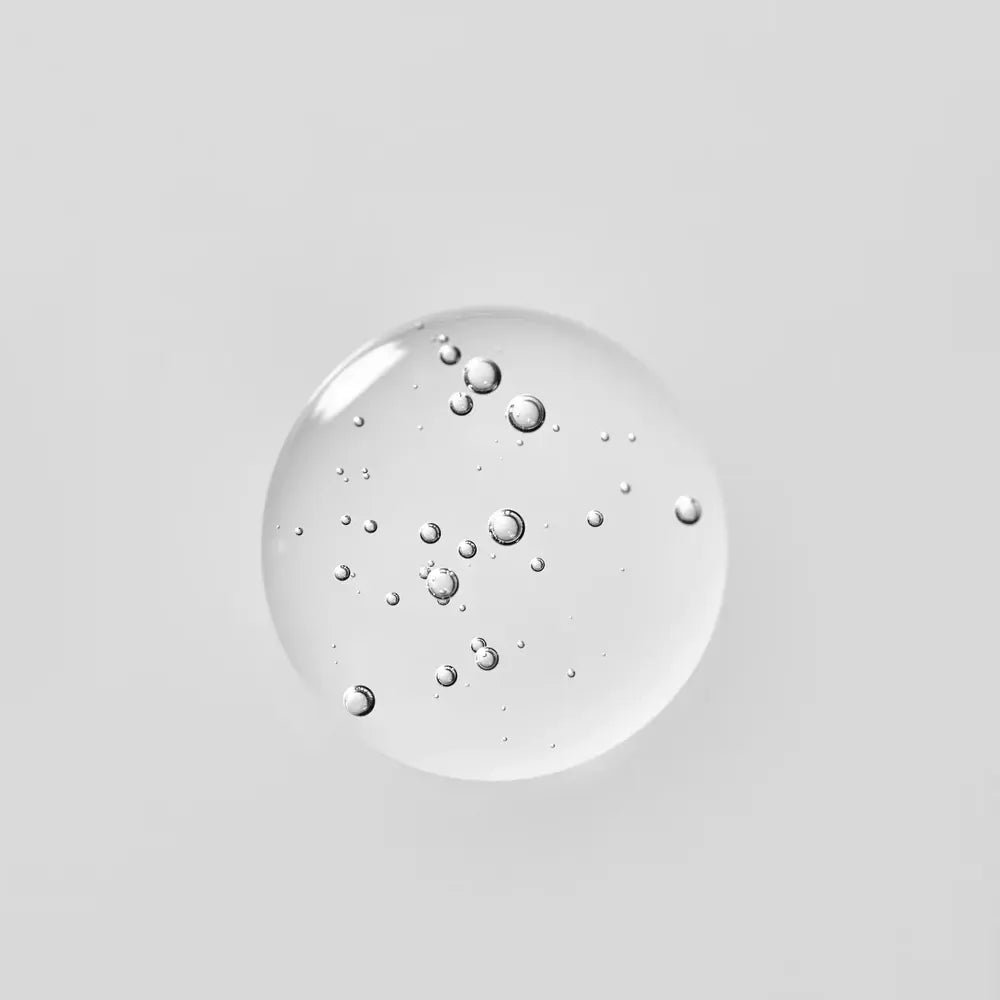 Young Goose Adaptogenic Cleanser droplet with embedded small bubbles, centered on a solid light gray background.