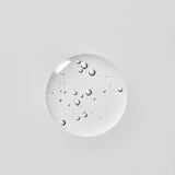 Young Goose Adaptogenic Cleanser droplet with embedded small bubbles, centered on a solid light gray background.