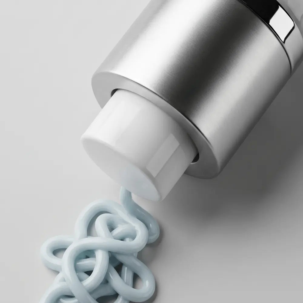 A close-up of Young Goose C.A.R.E. bottle dispensing a thick, pale blue cream onto a light gray surface.