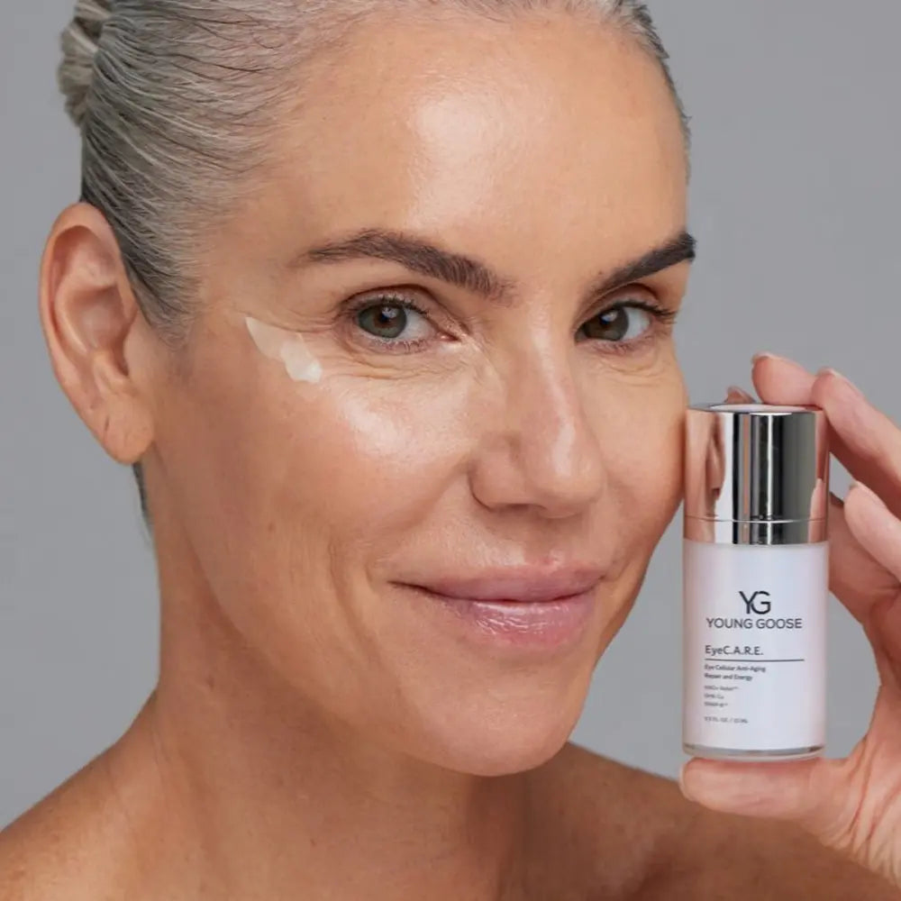 A close-up of a woman holding a bottle of Young Goose EyeC.A.R.E. eye treatment serum.