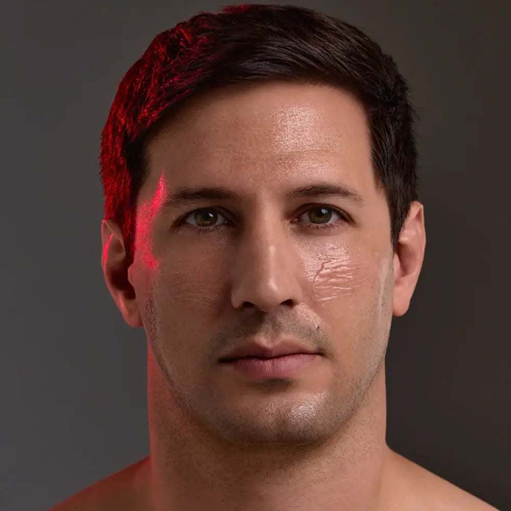 A close-up portrait of a man's face with dramatic red lighting highlighting his hair and cheek with Young Goose L.A.D.R. Serum