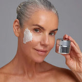 A woman with gray hair pulled back applies Young Goose NiaPolish to her cheek